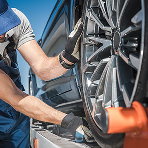 Worker securing car wheel on a tow truck Representing Car to Cover My Debt.