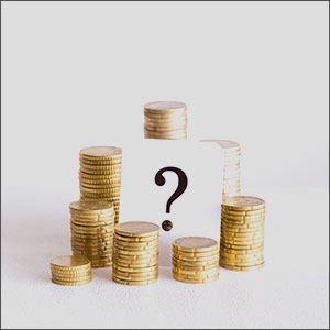 Stacked coins with a question mark on a white card, symbolizing financial uncertainty.