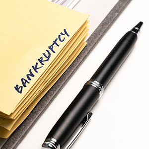 Stack of yellow sticky notes with 'BANKRUPTCY' written on the top one, next to a pen.