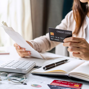 Person reviewing credit card bill, calculator, and credit cards, for managing tax debts.