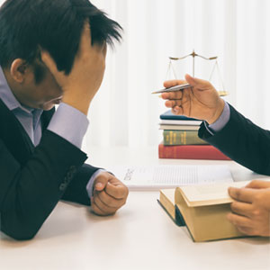 Lawyer advising distressed client with scales of justice in background, for bankruptcy ease.