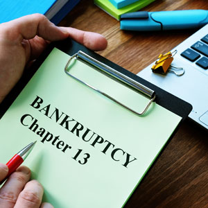 Hand holding a clipboard with 'BANKRUPTCY Chapter 13' and a red pen, representing post-bankruptcy credit.