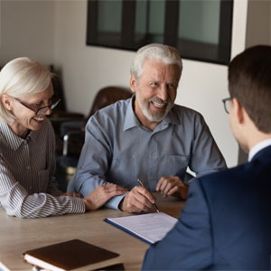 A smiling senior couple reviews documents with an attorney, symbolizing bankruptcy discussions.
