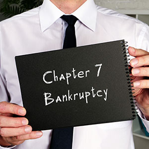 Man holds a sign saying 'Chapter 7 Bankruptcy'.