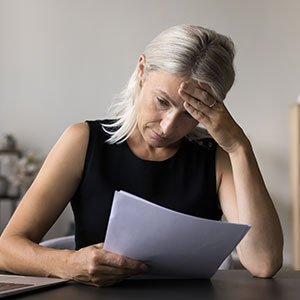 Distressed woman holding papers, representing creditor harassment.